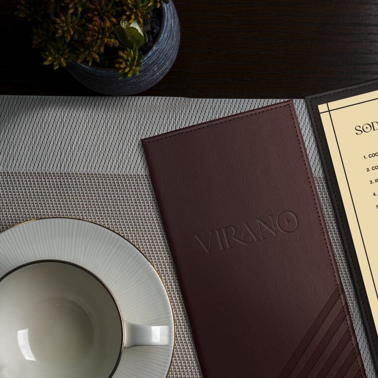 Carte en cuir marron du restaurant Virano, avec une plante en haut et une tasse de thé à gauche.